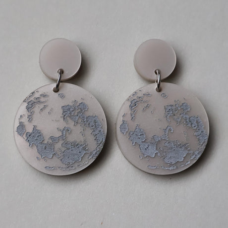 Pair of round moon earrings depicting its southern hemisphere orientation
