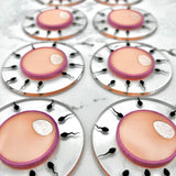 Array of multiple egg and sperm acrylic brooches.