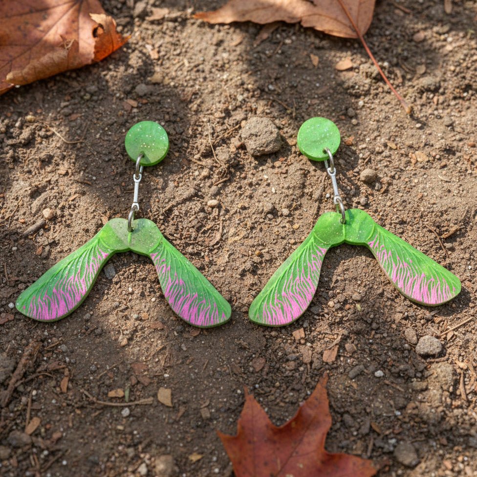 A pair of maple samara helicoper seed earrings made from green acrylic with round earring toppers. 