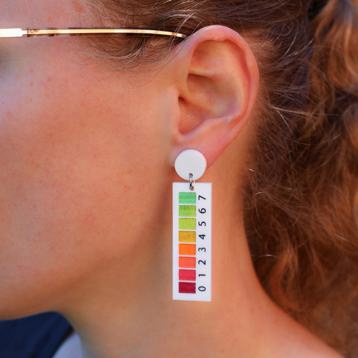 A woman modelling a pair of pH indicator earrings 
