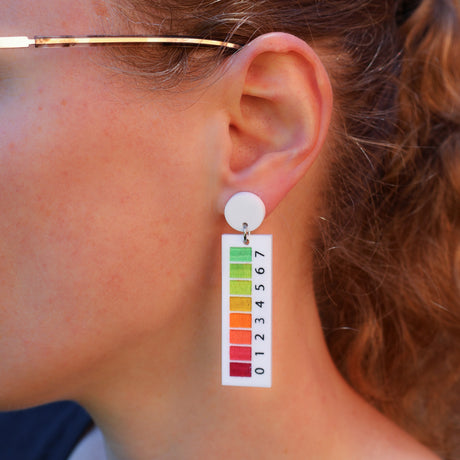 A woman modelling a pair of pH indicator earrings 