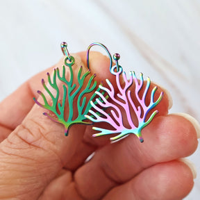 Small Colorful coral-shaped earrings held between fingers against a white background