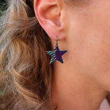 Close-up of a person wearing a colorful star-shaped earring.
