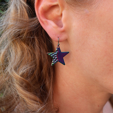 Close-up of a person wearing a colorful star-shaped earring.