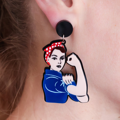 Rosie the Riveter Earrings in light skin tone with brown hair, laser cut acrylic on black toppers, worn on a model’s earlobe