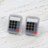 Calculator-shaped acrylic studs on a textured white surface