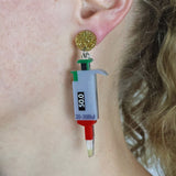 Earring shaped like a micropipette in christmas colours worn on an ear