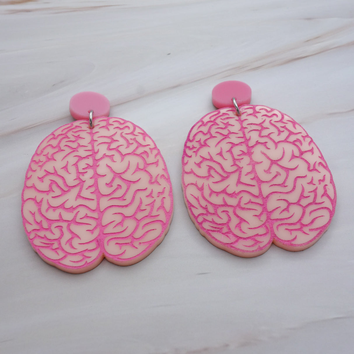 A pair of realistic looking brain earrings in light pink acrylic, with hot pink painted details. Laser cut from acrylic.