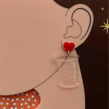 Laser Cut Acrylic Clear Beaker Earrings with Red Heart Earring Toppers. Chemistry Glassware Earrings modelled. 