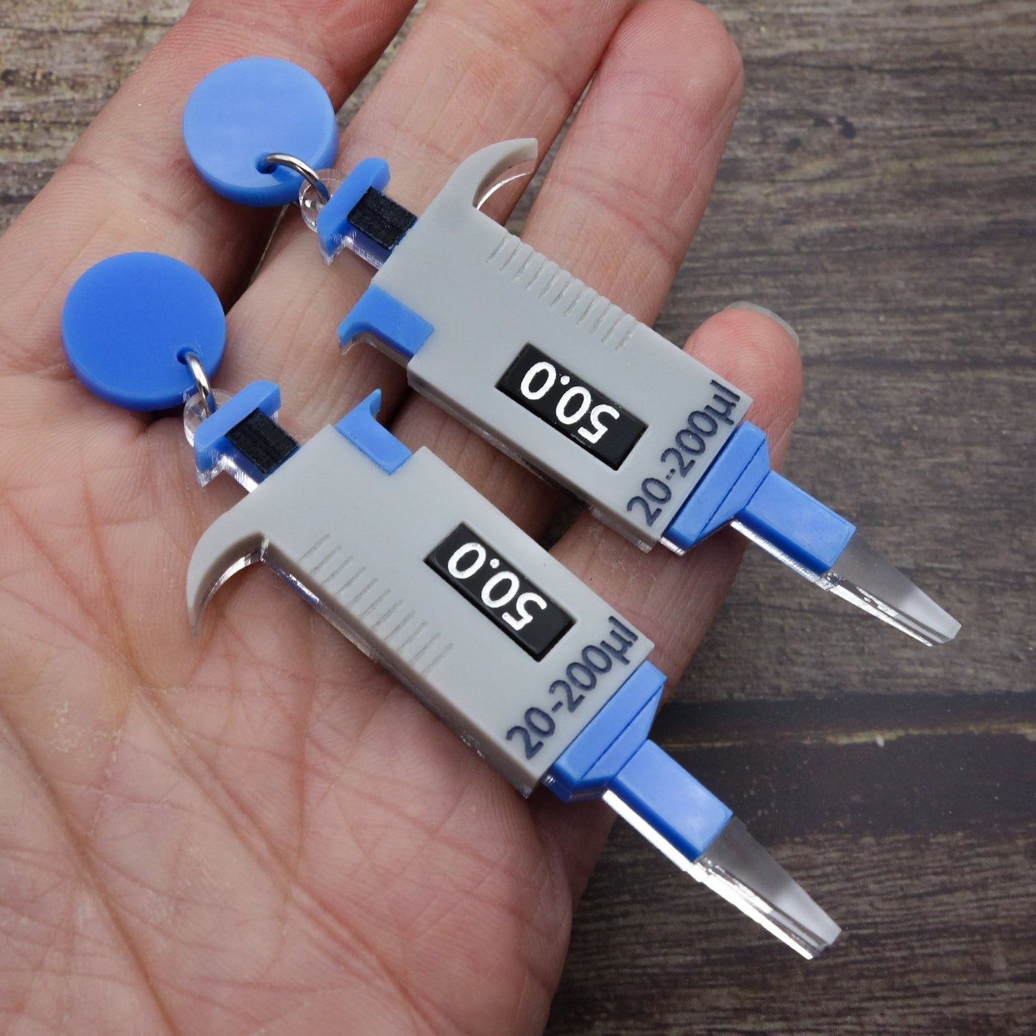 Grey and blue micropipette earrings laser cut and handpainted from acrylic. They hang from blue earring toppers.