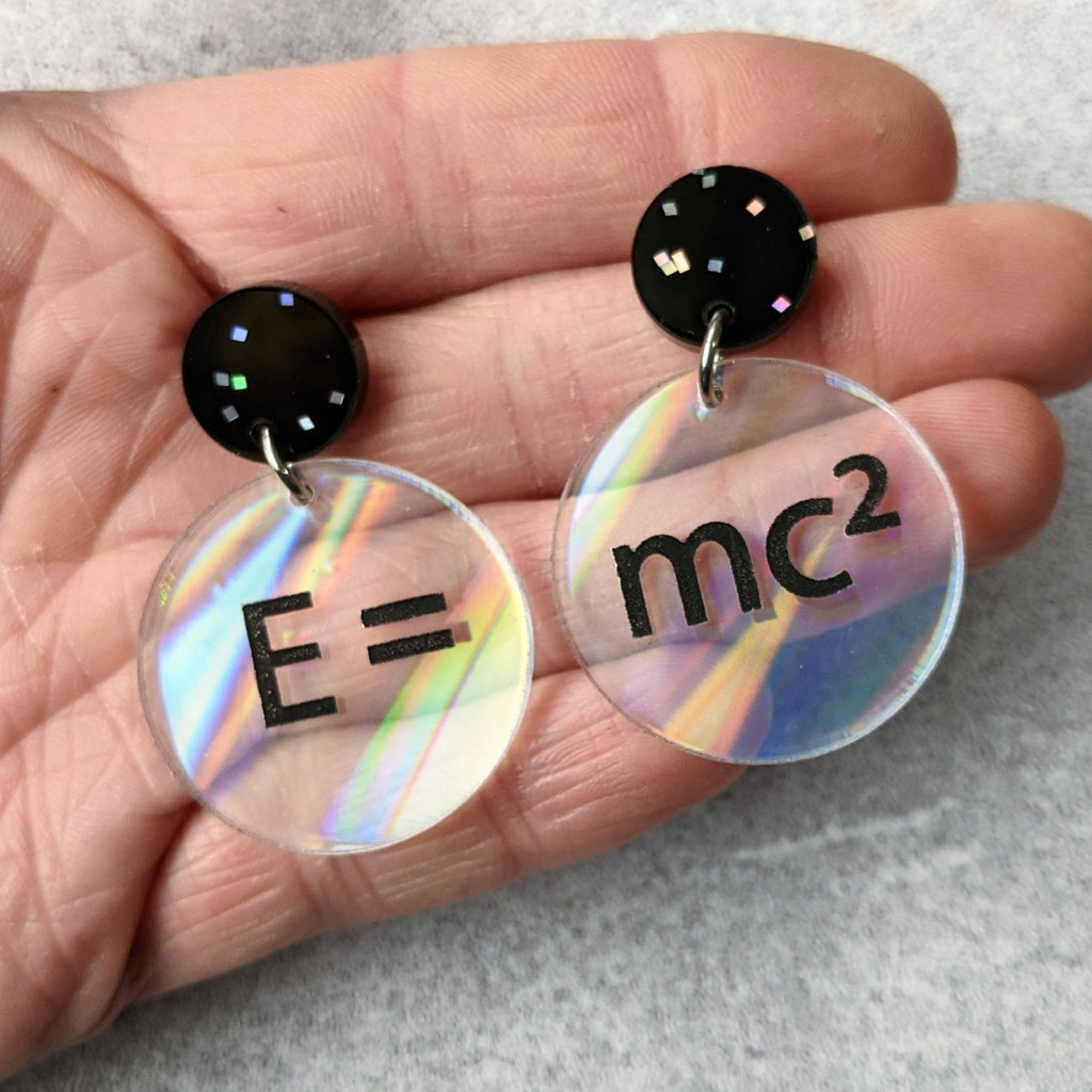 E =mc2 earrings, with black text engraved into holographic effect acrylic discs. Equation bridges both earrings. Black glitter earring toppers.