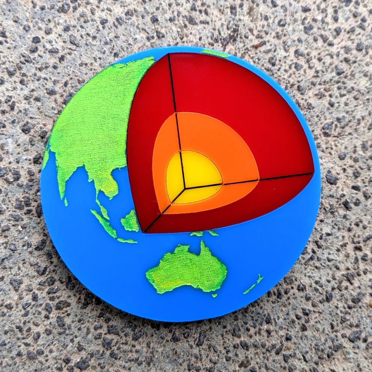 Laser Cut Acrylic Planet Earth Brooch with Core Cutout up close. 