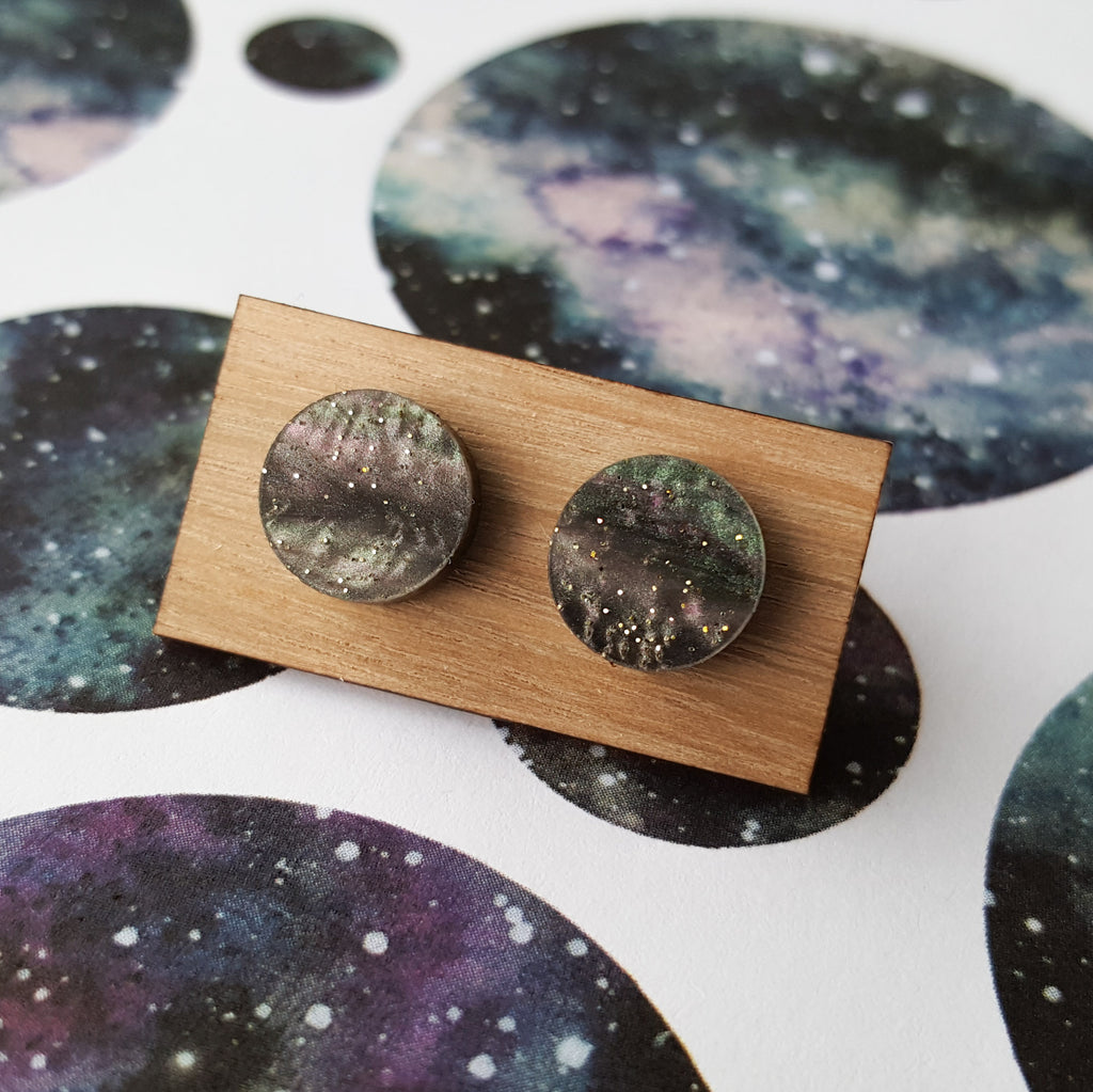 A pair of small acrylic studs on a wooden backing card.