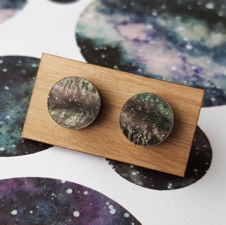 A pair of small acrylic studs on a wooden backing card.