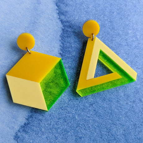 Asymmetrical geometric earrings, comprising of a statement sized cube and triangle in three different yellow toned laser cut acrylics.