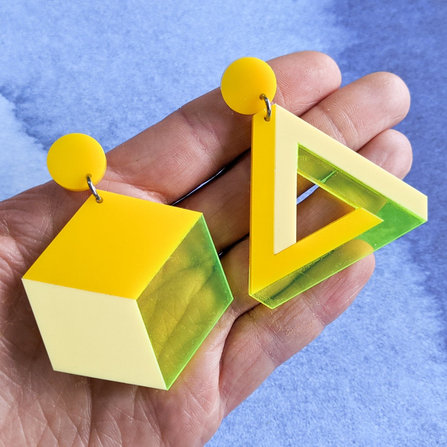 Asymmetrical geometric earrings, comprising of a statement sized cube and triangle in three different yellow toned laser cut acrylics.