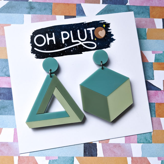 Asymmetrical geometric earrings, comprising of a statement sized cube and triangle in three different green toned laser cut acrylics.