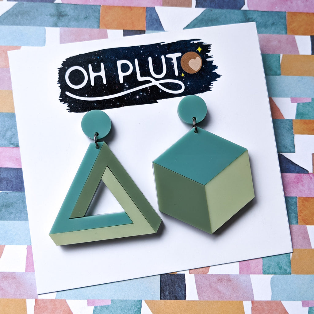 Asymmetrical geometric earrings, comprising of a statement sized cube and triangle in three different green toned laser cut acrylics.