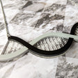 A partial view of a DNA necklace, in greyscale, handmade from laser cut acrylic.