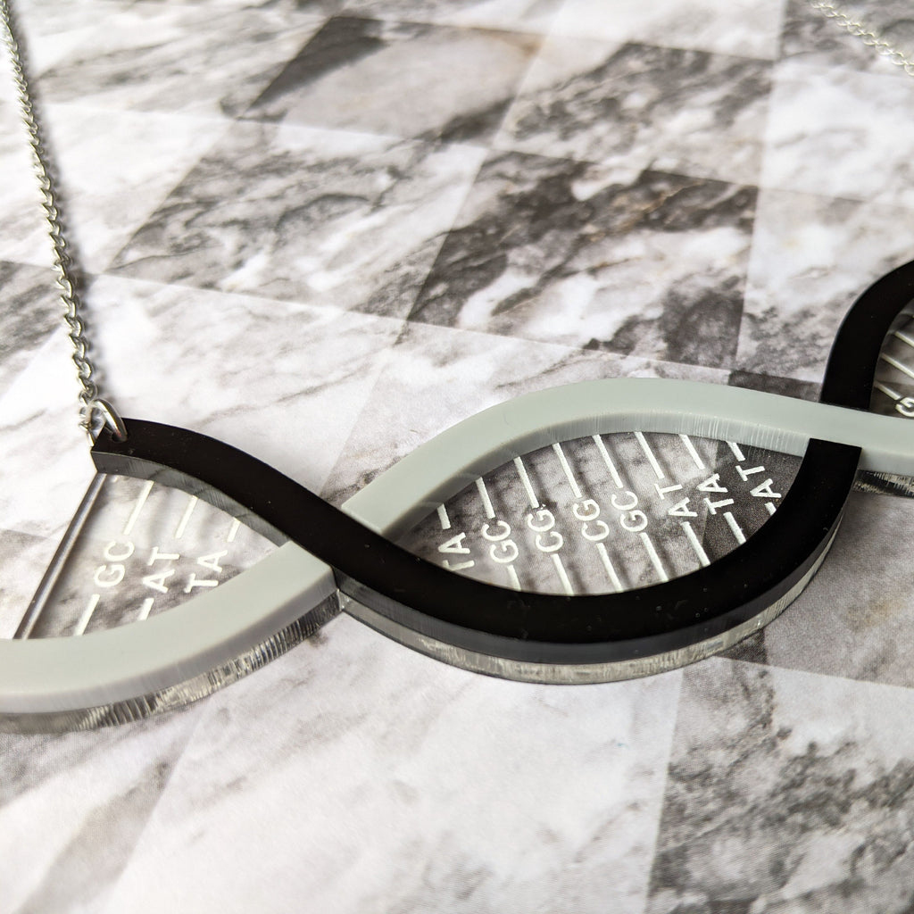 A partial view of a DNA necklace, in greyscale, handmade from laser cut acrylic.