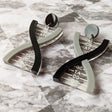 A pair of DNA earrings in greyscale, handmade from laser cut acrylic.