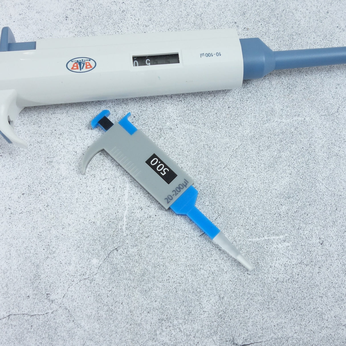 Acrylic micropipette brooch next to a real micropipette