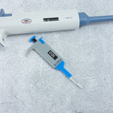Acrylic micropipette brooch next to a real micropipette