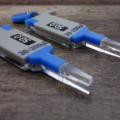 Closeup view of acrylic micropipette earrings in blue and grey.