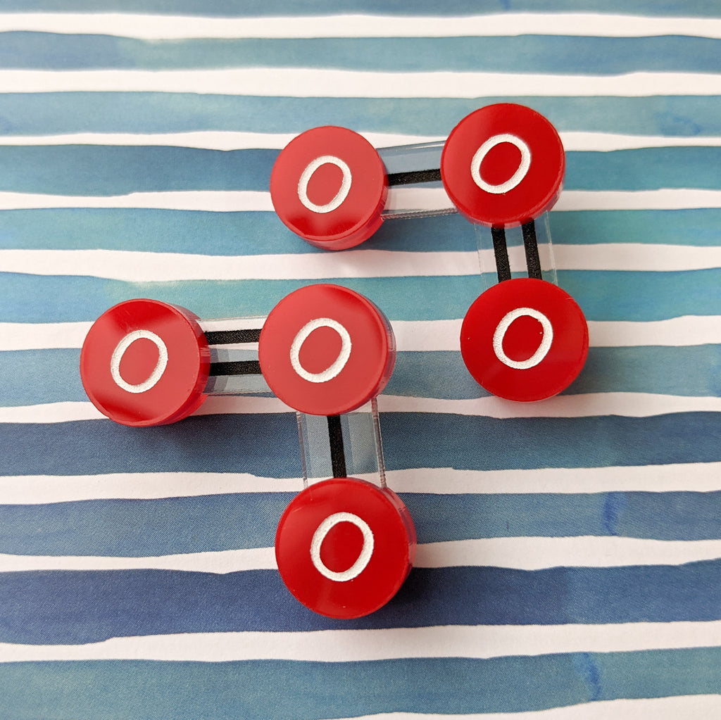 Laser cut acrylic ozone molecule studs, with red oxygen atoms and black molecular bonds.