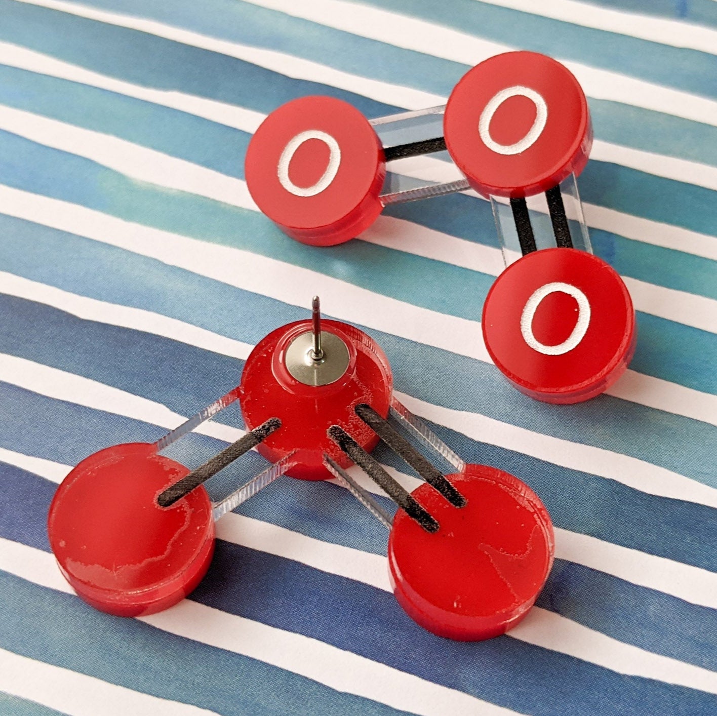 Laser cut acrylic ozone molecule studs, with red oxygen atoms and black molecular bonds. Back earring view showing the stainless steel earring post.
