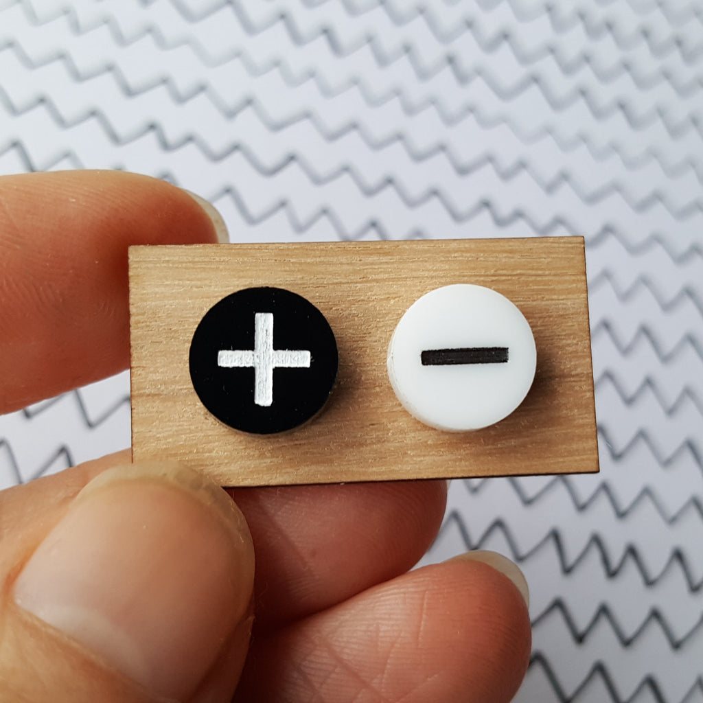 A pair of black and white 'positive and negative' studs on a wooden earring card. Laser cut from acrylic. 