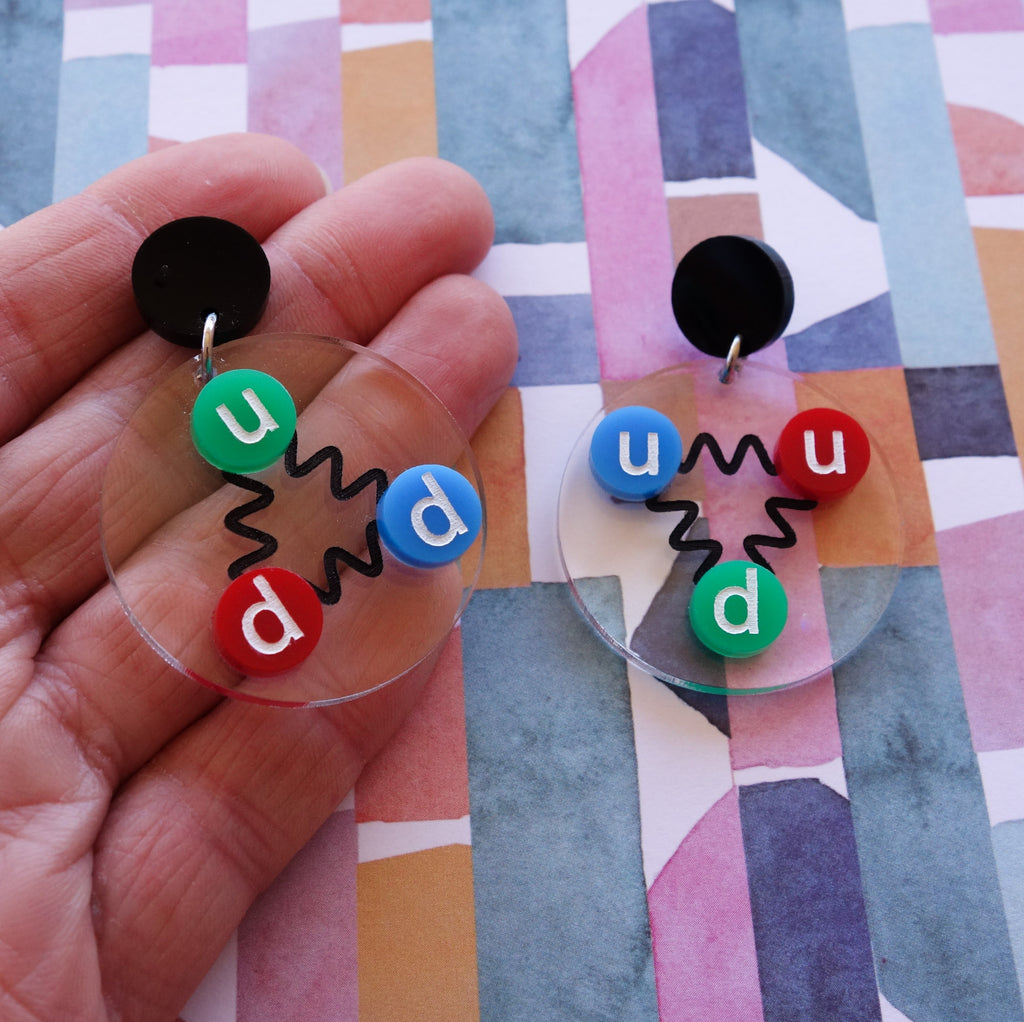 Laser cut acrylic quark earrings, , with green, red and blue up and down quarks, and hanging from black earring toppers.
