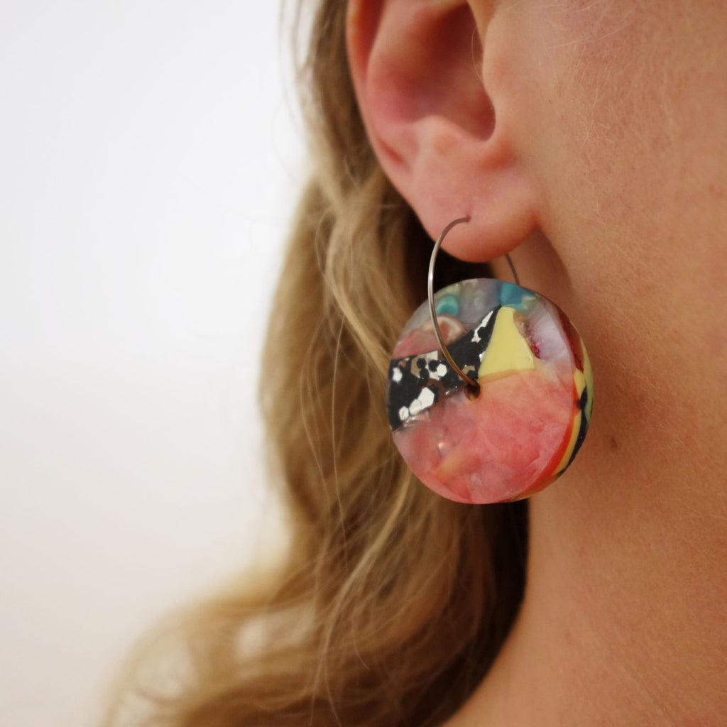 Disc shaped recycled plastic arylic earrings being modelled