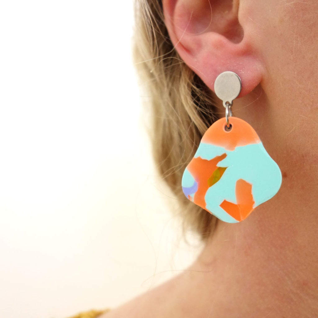 Organic shaped recycled plastic arylic earrings being modelled