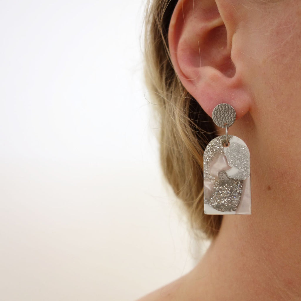 Small arch shaped recycled plastic arylic earrings being modelled