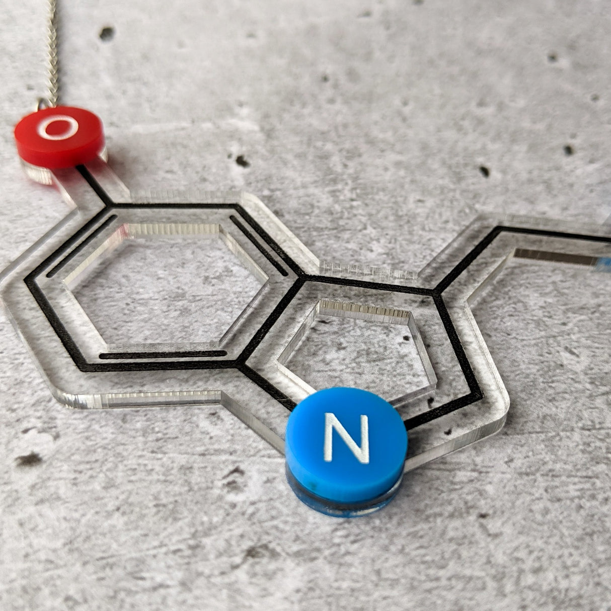 Closeup view of an Acrylic Serotonin necklace against a concrete background