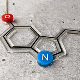 Closeup view of an Acrylic Serotonin necklace against a concrete background