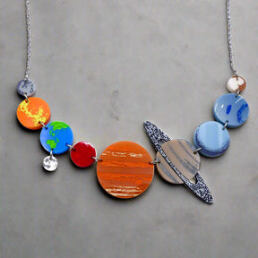 A solar system necklace, showing Mercury, Venus, Earth, the moon, Mars, Jupiter, Saturn, Uranus, Neptune and Pluto in differently coloured acrylics with handpainted highlights.