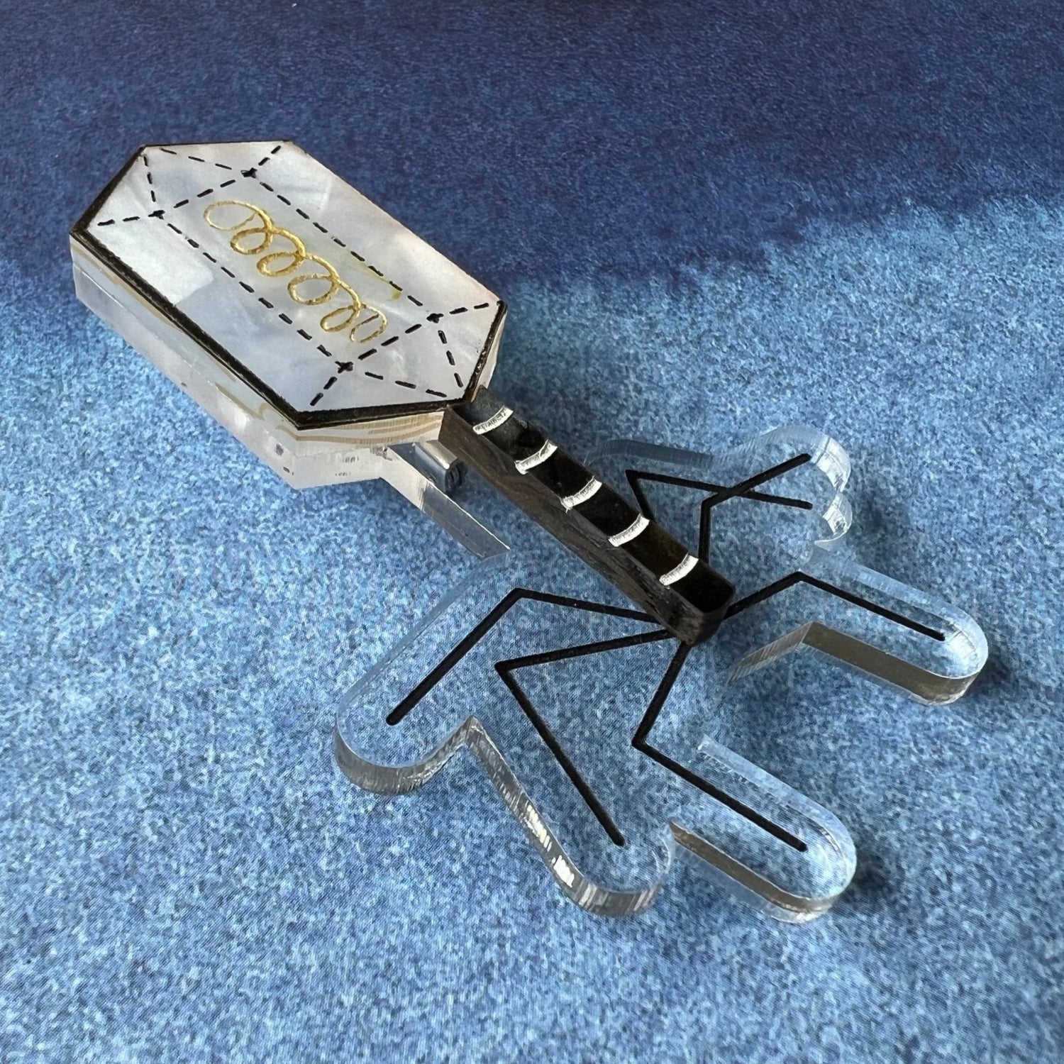 An angled view of a virus (bacteriophage) brooch, handmade from laser cut acrylic.