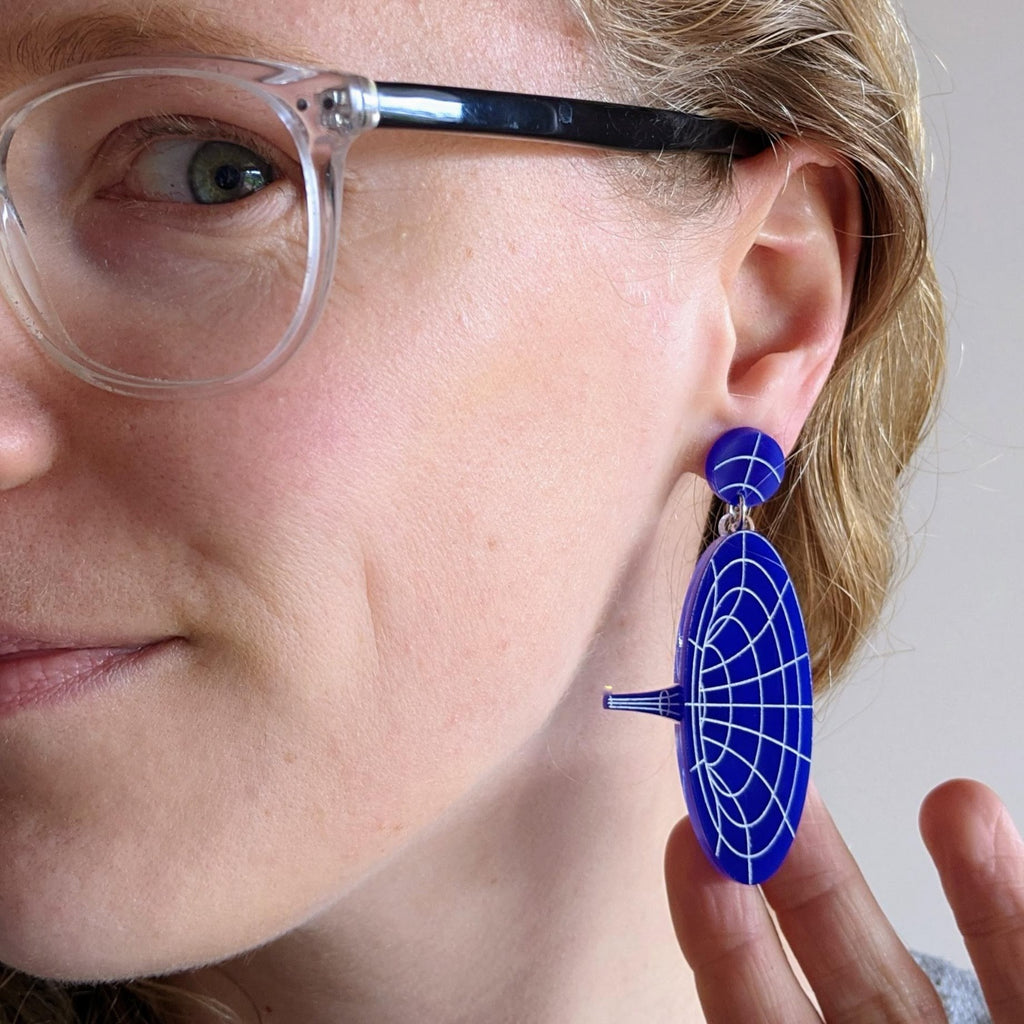 Dark blue dangle acrylic wormhole earrings being modelled.